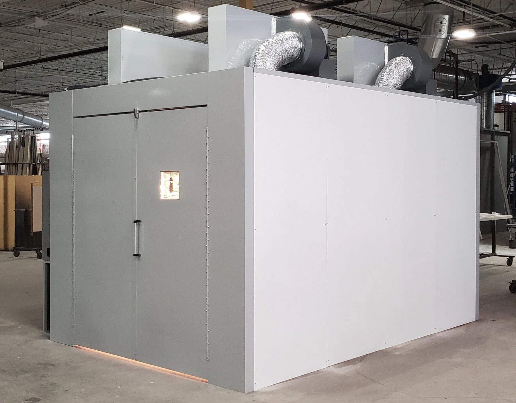 Large industrial Halcon Batch Oven enclosure with sliding door and ducting systems in a warehouse.